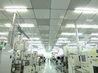 A picture of a imec cleanroom, a long hall in the middle with people walking alongside white machines.