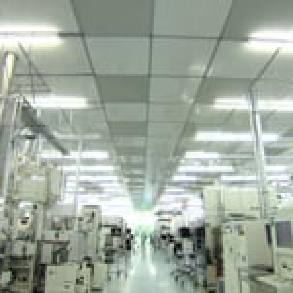 A picture of a imec cleanroom, a long hall in the middle with people walking alongside white machines.